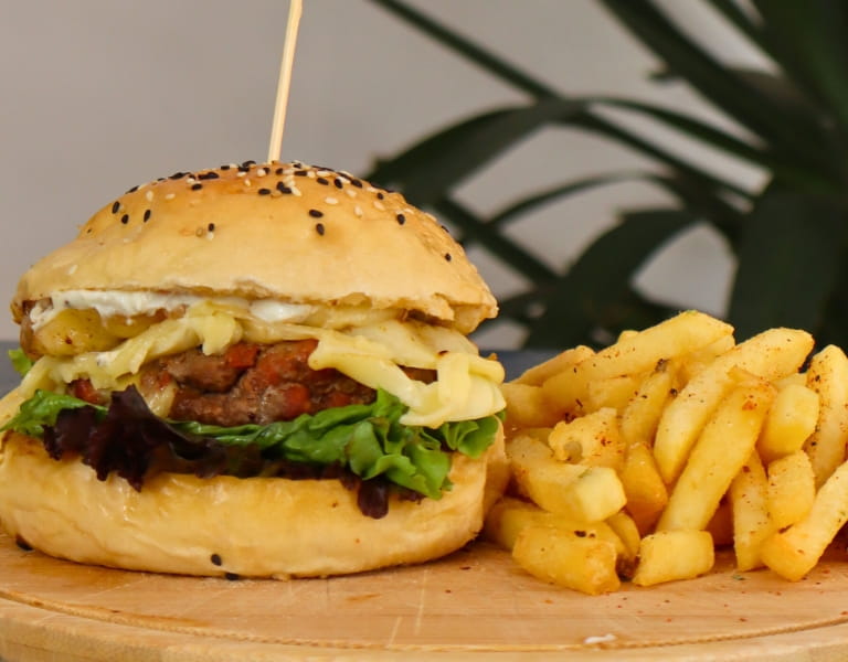 Hamburguesa con queso, lechuga y papas fritas sobre tabla de madera