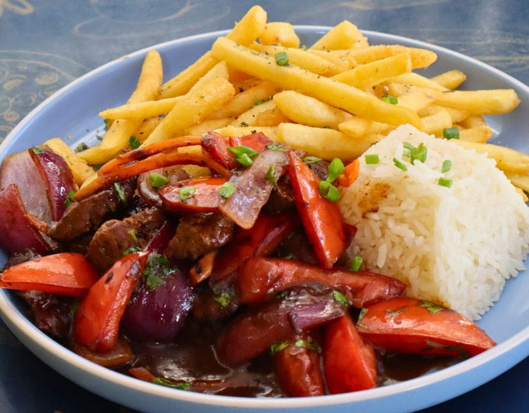 Lomo saltado con arroz y papas fritas servido en plato azul